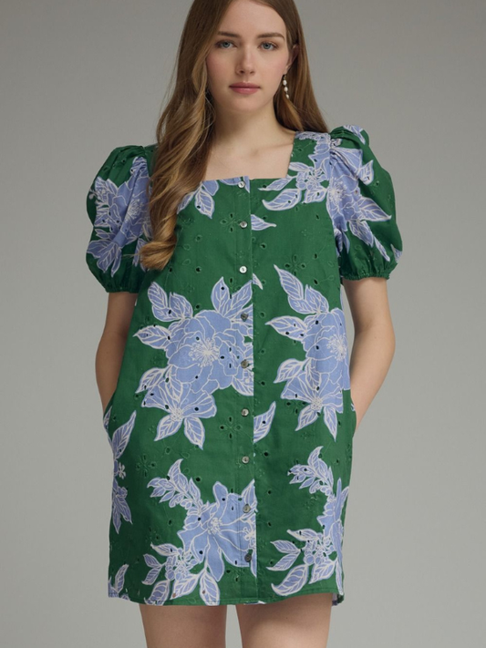 Woman wearing a green dress with blue floral patterns on a gray background