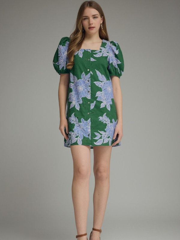 Woman wearing a green floral dress against a gray background