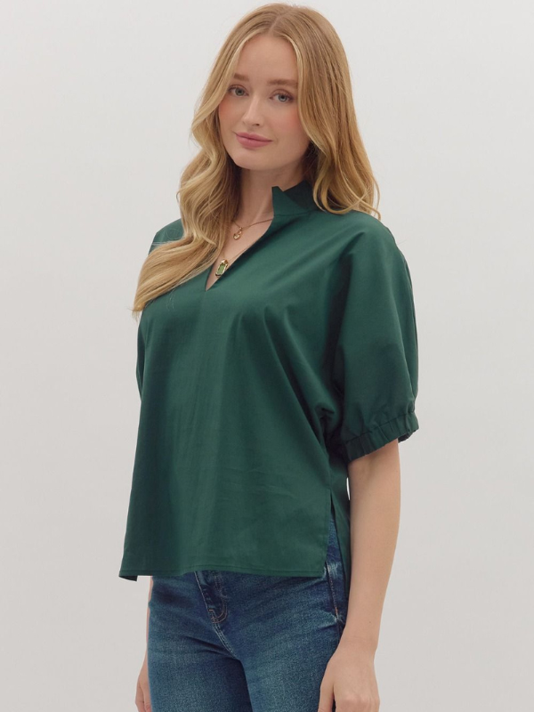 Woman wearing a green blouse and blue jeans against a plain background