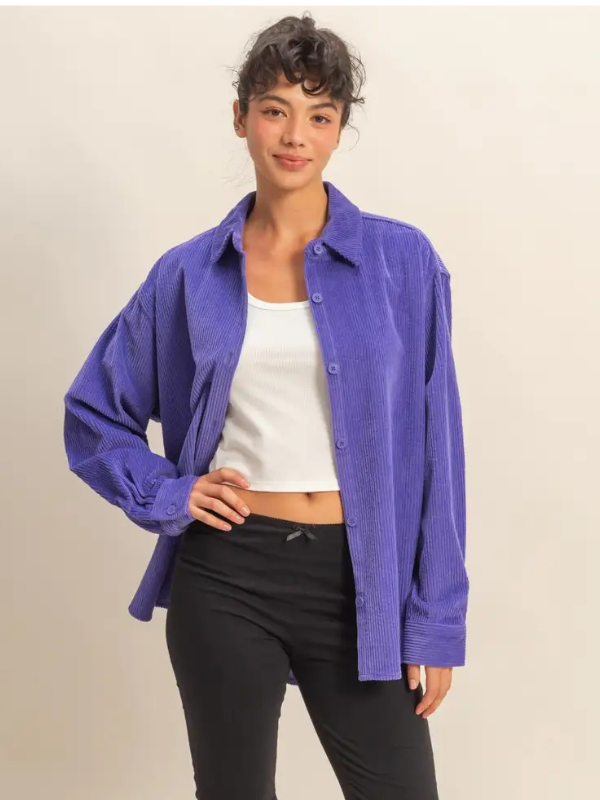 Person wearing a purple shirt over a white top and black pants on a beige background
