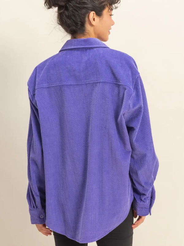 Person wearing a purple corduroy shirt against a beige background