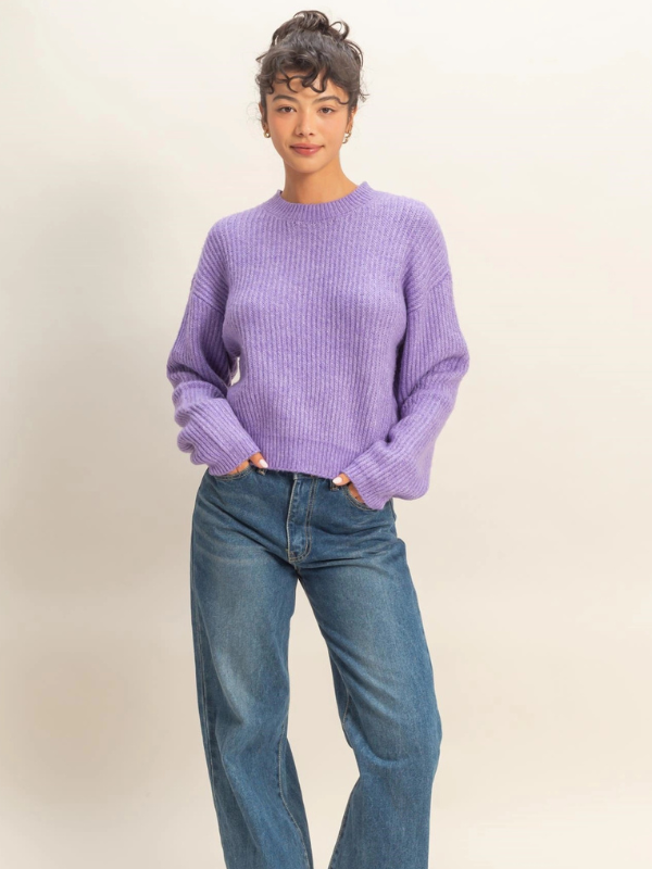 Person wearing a purple sweater and blue jeans on a plain background