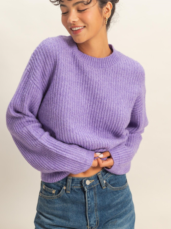 Person wearing a purple sweater and blue jeans on a plain background