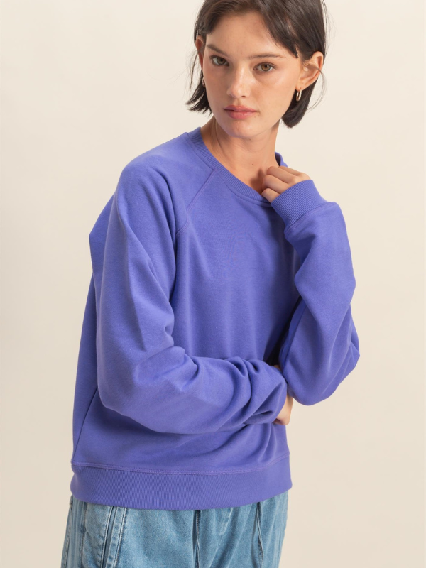 Person wearing a blue sweater and light blue pants on a beige background
