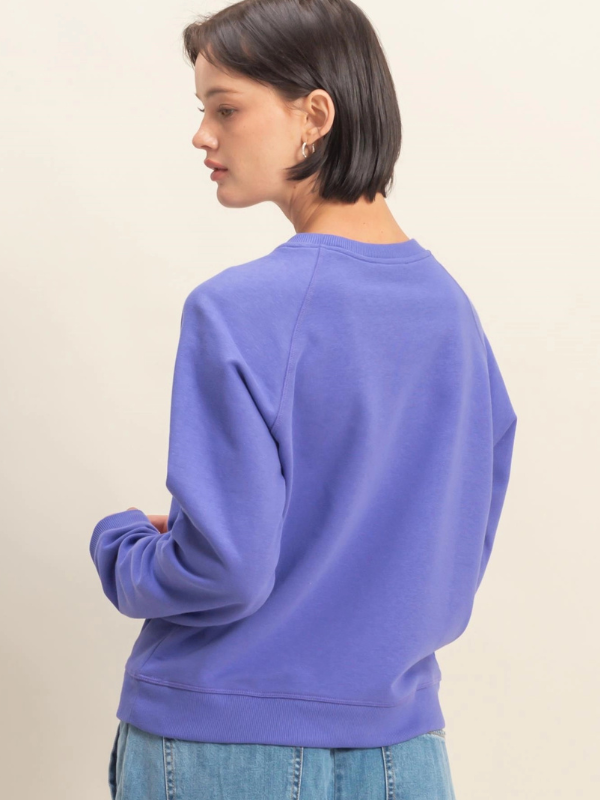 Person wearing a purple sweatshirt against a beige background