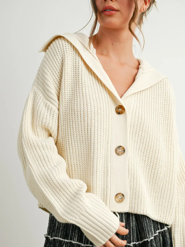 Cream-colored knitted cardigan with buttons on a plain background