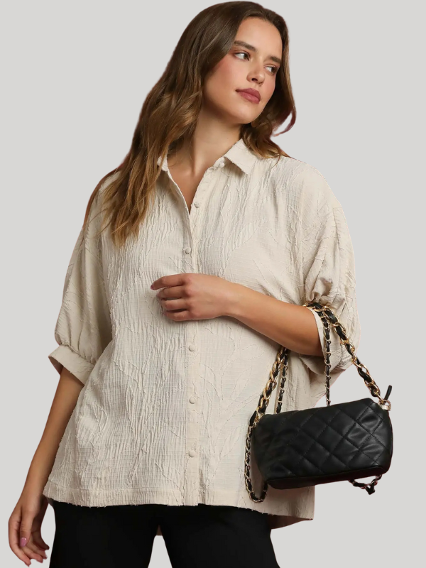 Woman holding a black quilted handbag against a plain background