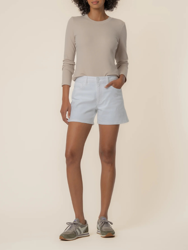 Person wearing a beige long-sleeve shirt and light blue shorts on a beige background