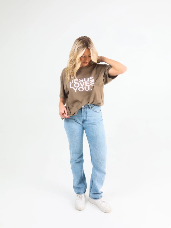 Woman wearing a t-shirt with 'Jesus Loves You' text on a plain background