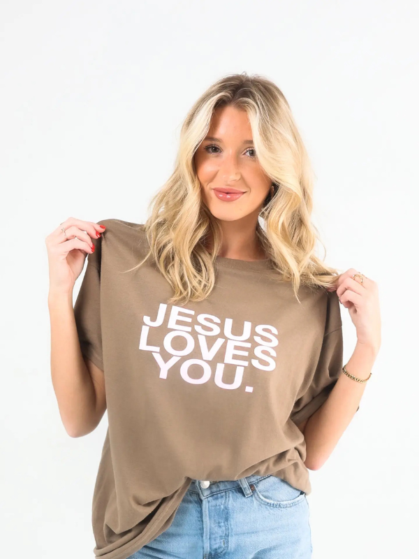 Woman wearing a brown t-shirt with 'Jesus Loves You' text on a white background