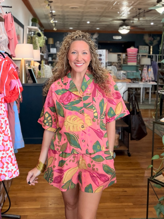 Woman wearing a pink floral top and shorts in a store setting
