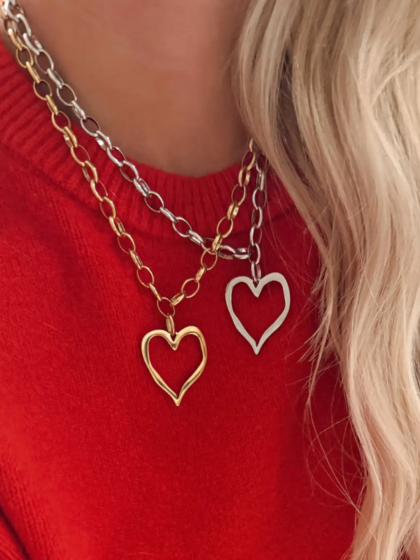 Two heart-shaped pendants on gold chains against a red background