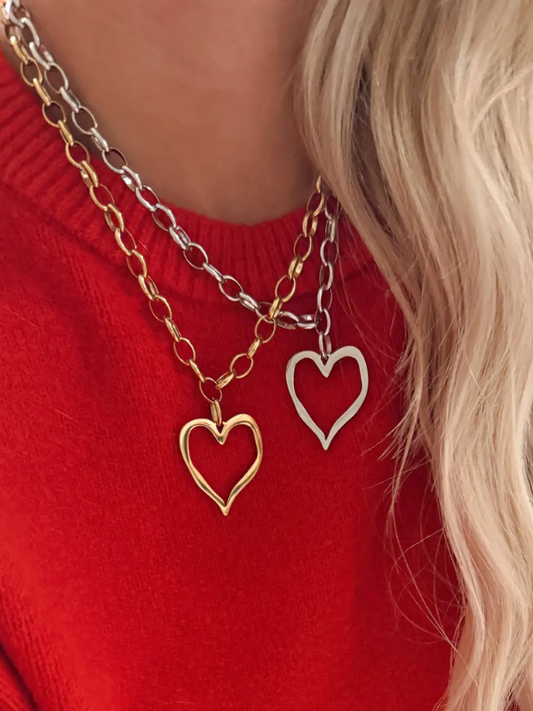 Two heart-shaped pendants on gold chains against a red background