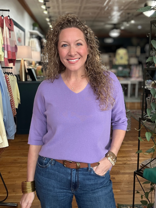 Woman wearing a purple shirt and blue jeans in a store setting