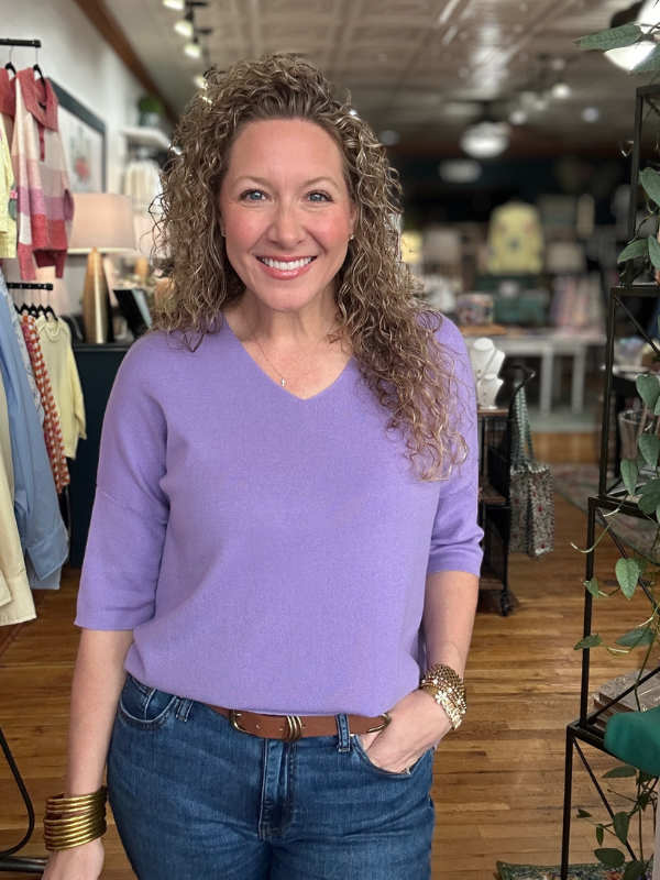 Woman wearing a purple sweater and blue jeans in a store setting