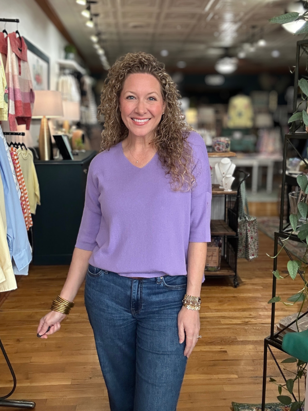 Woman wearing a purple sweater and blue jeans in a store setting
