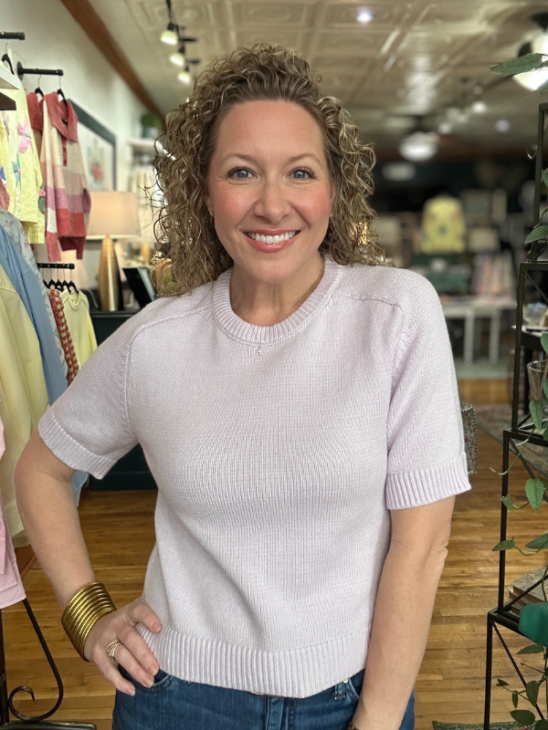 Woman wearing a light purple sweater in a store setting