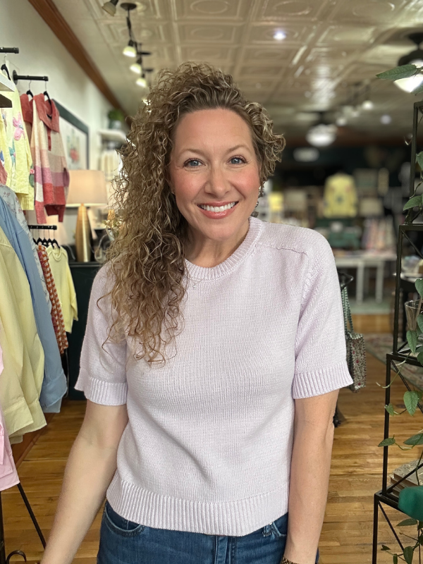 Woman wearing a light purple sweater in a store setting