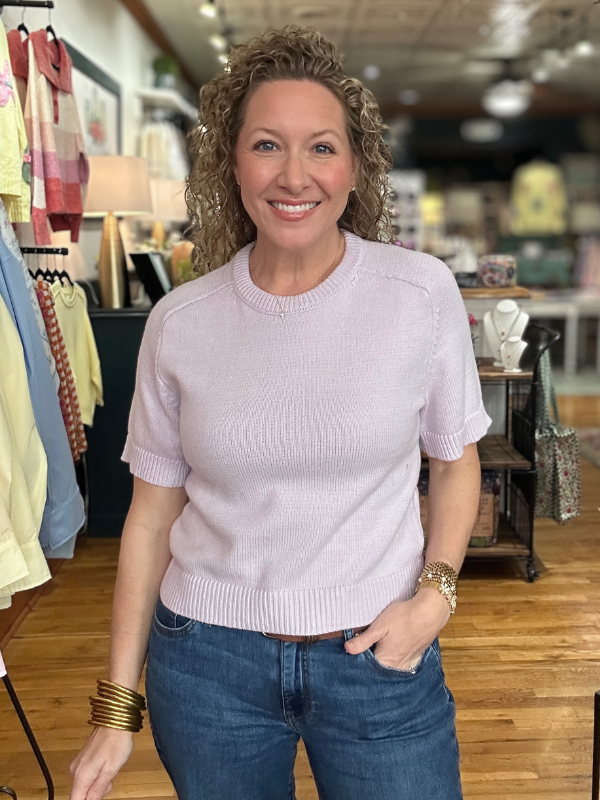 Woman wearing a light purple sweater and blue jeans in a store setting