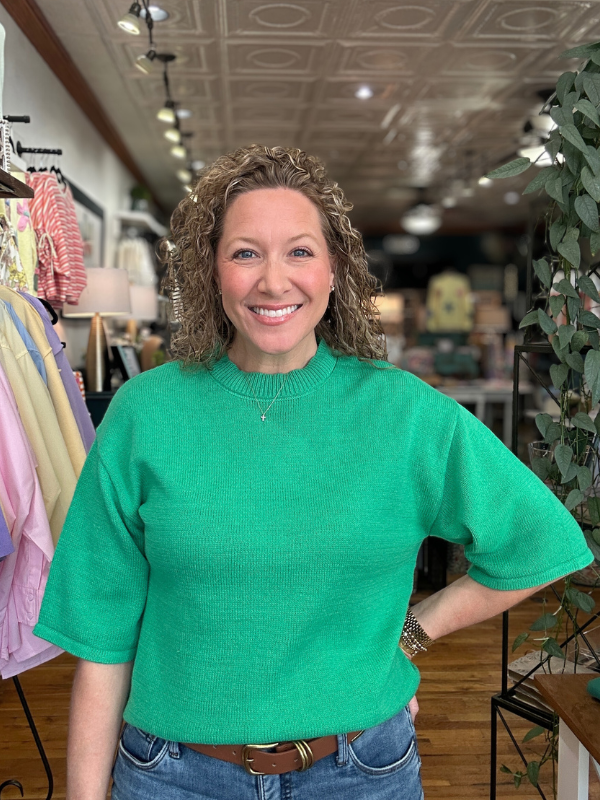 Woman wearing a green sweater in a store setting