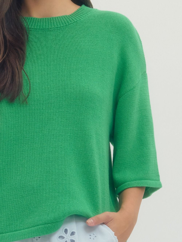 Green sweater worn by a person on a plain background