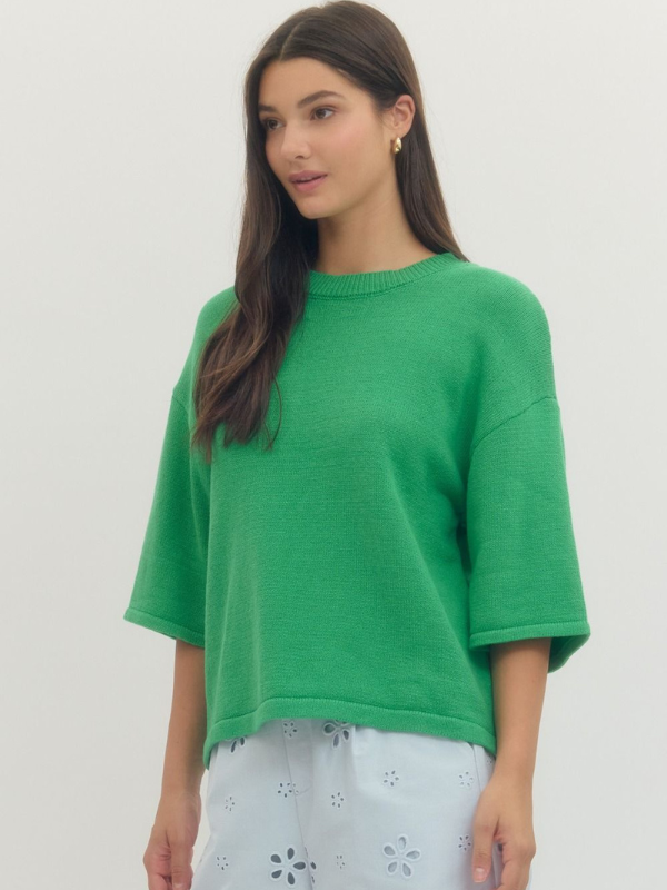 Woman wearing a green sweater against a plain background