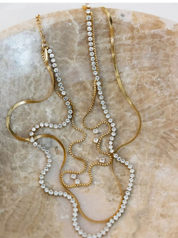 Gold and pearl necklace on a textured beige surface