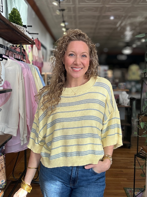 Woman wearing a yellow striped sweater in a store setting