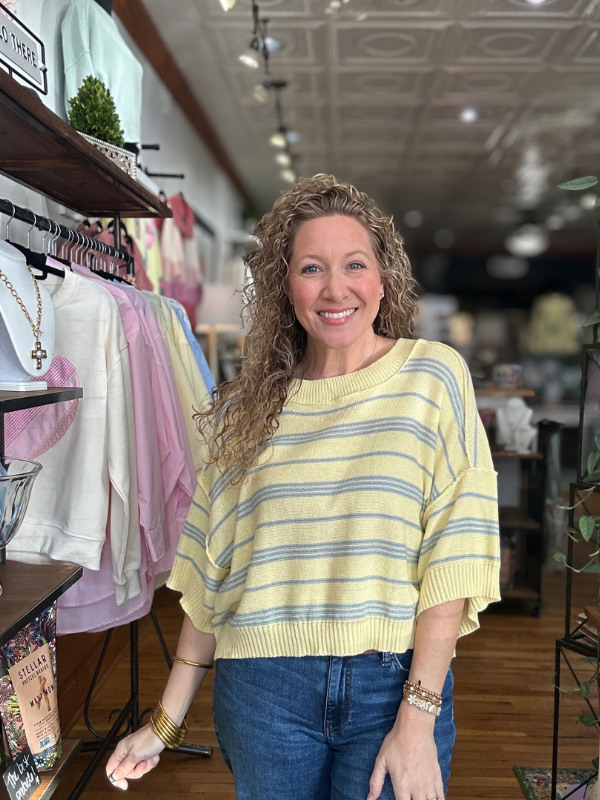 Woman wearing a yellow striped sweater in a store setting