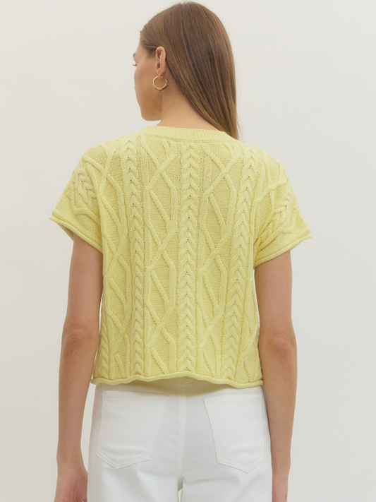 Woman wearing a light green knitted top against a white background