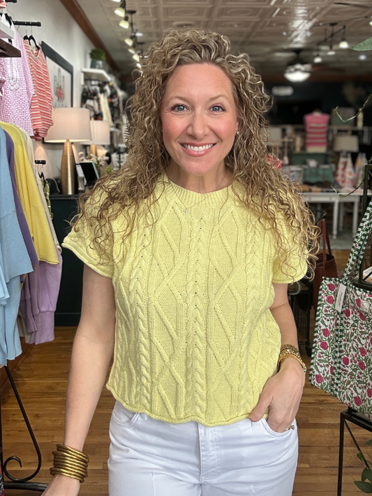 Woman wearing a yellow cable knit shirt in a store setting