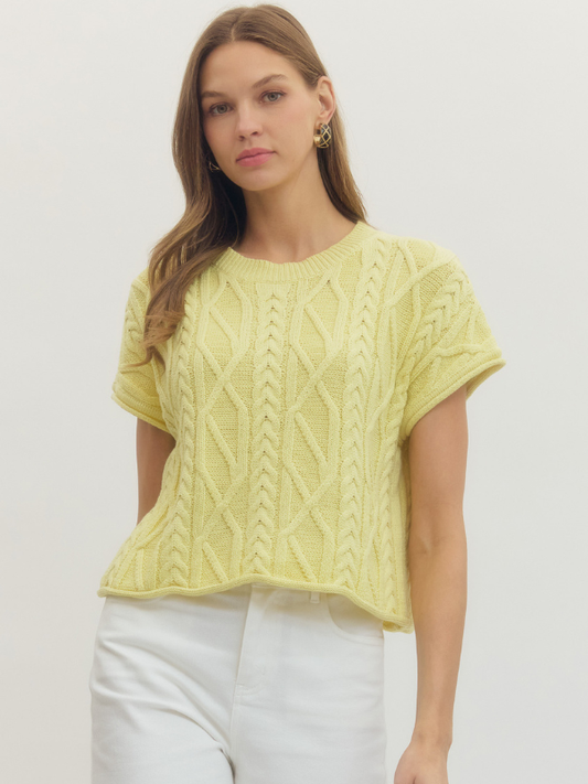 Woman wearing a yellow knitted top against a plain background