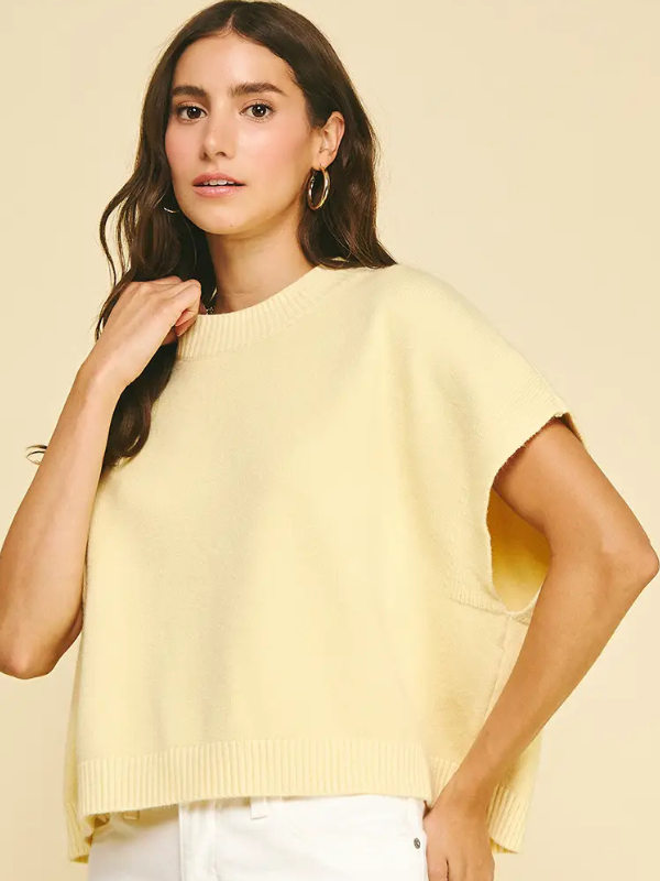 Woman wearing a light yellow sweater against a beige background