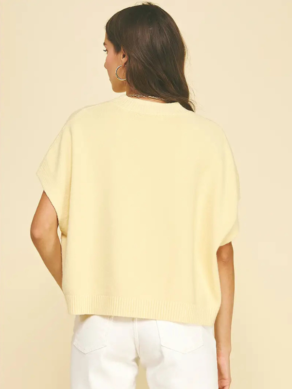 Person wearing a light yellow sweater and white pants on a beige background