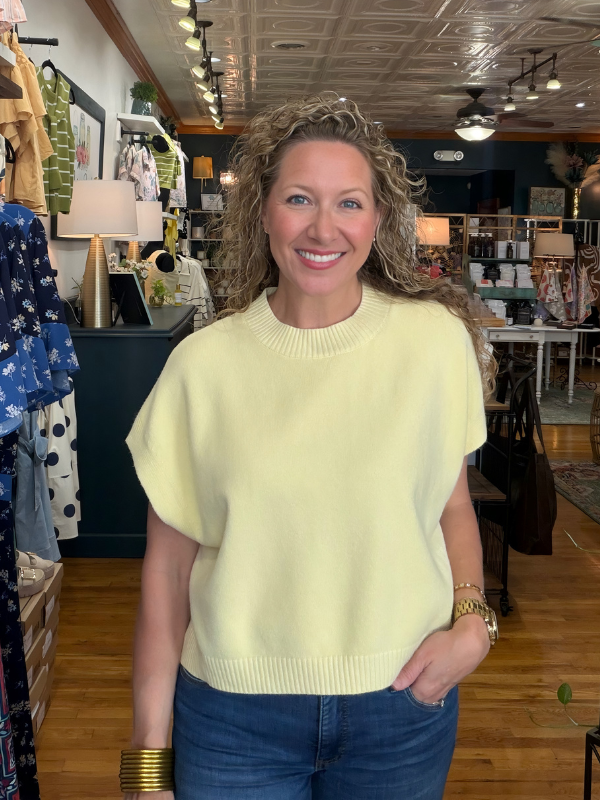 Woman wearing a light yellow sweater and blue jeans in a store setting