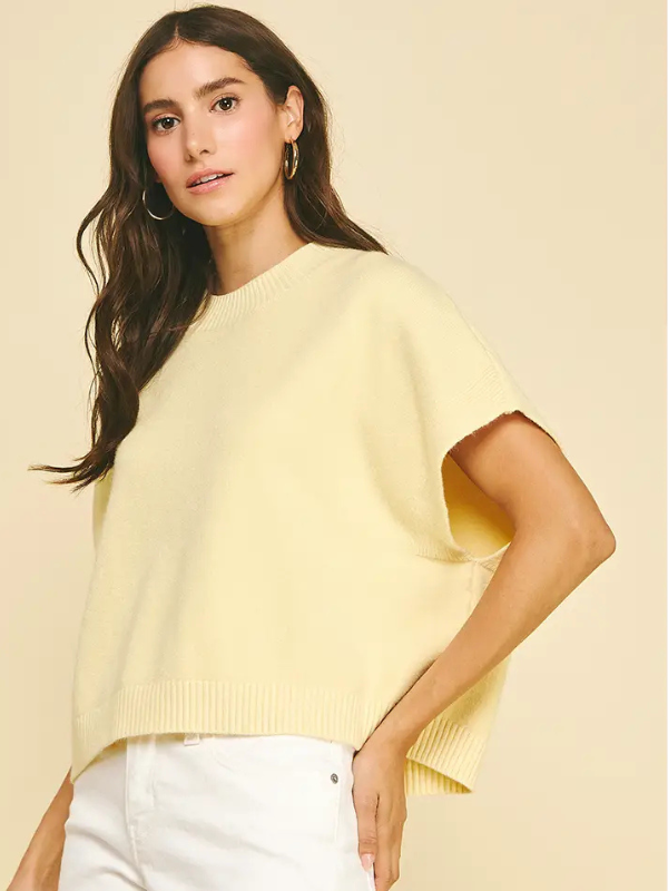 Woman wearing a light yellow sweater against a beige background