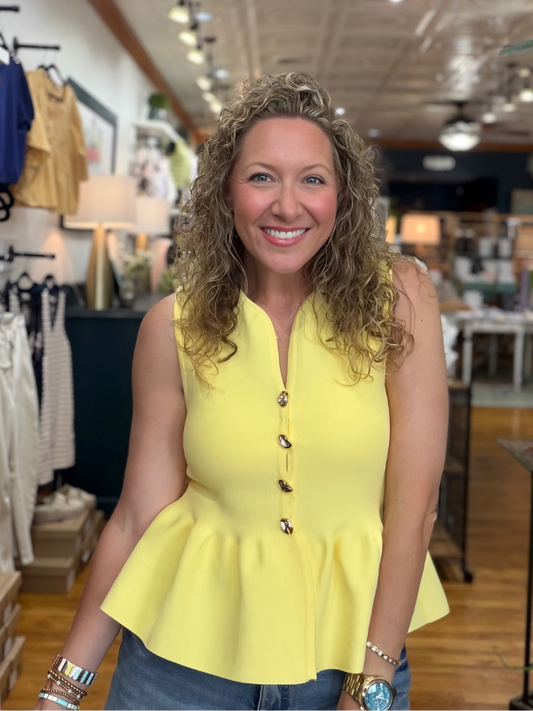 Woman wearing a yellow peplum top in a store setting