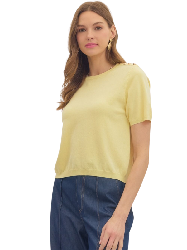 Woman wearing a yellow top with embellishments on a white background