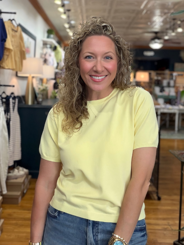 Woman wearing a yellow shirt and blue jeans in a store setting