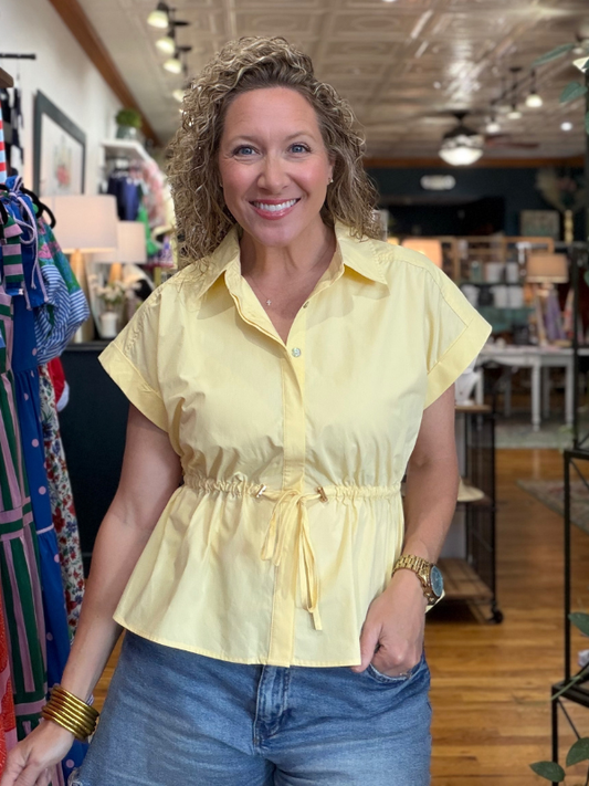 Woman wearing a yellow blouse and blue jeans in a store setting