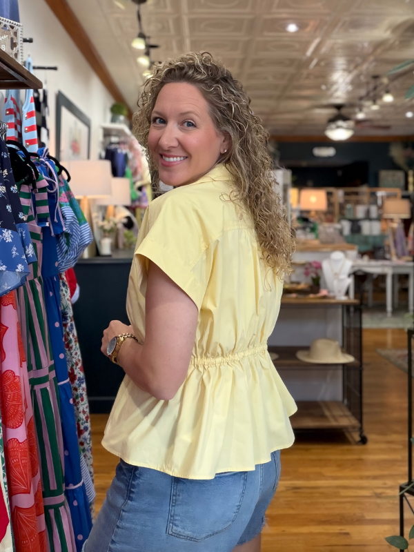 Woman wearing a yellow blouse in a store setting