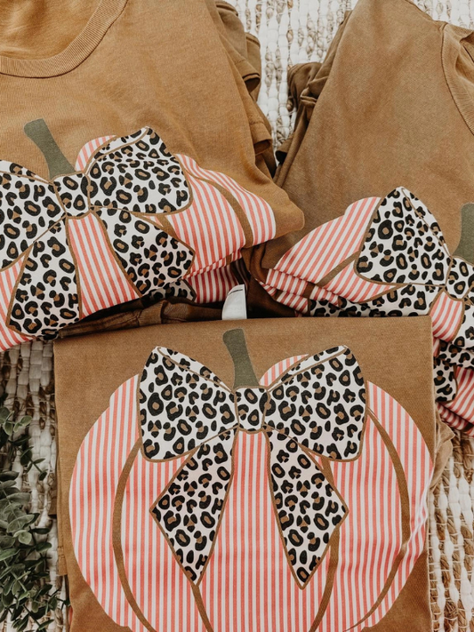 Brown shirts with leopard print and striped bows on a wooden surface
