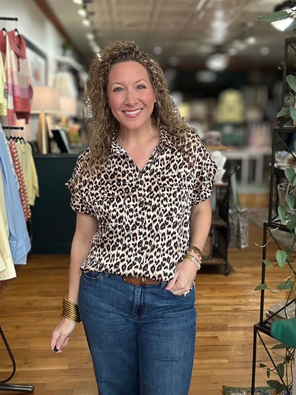 Woman wearing a leopard print shirt and blue jeans in a store setting