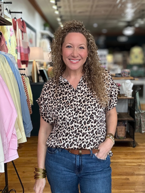 Woman wearing a leopard print blouse and blue jeans in a store setting