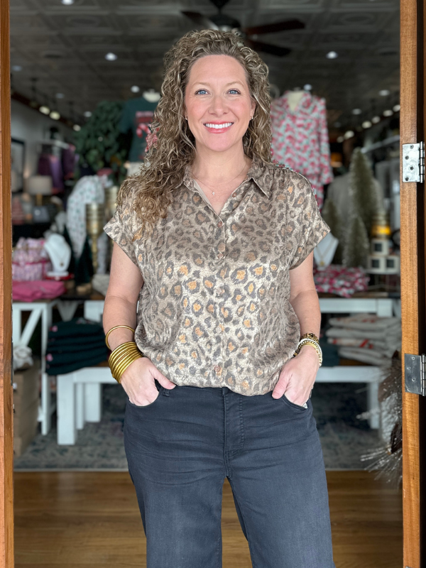Woman wearing a patterned blouse and jeans standing in a store.