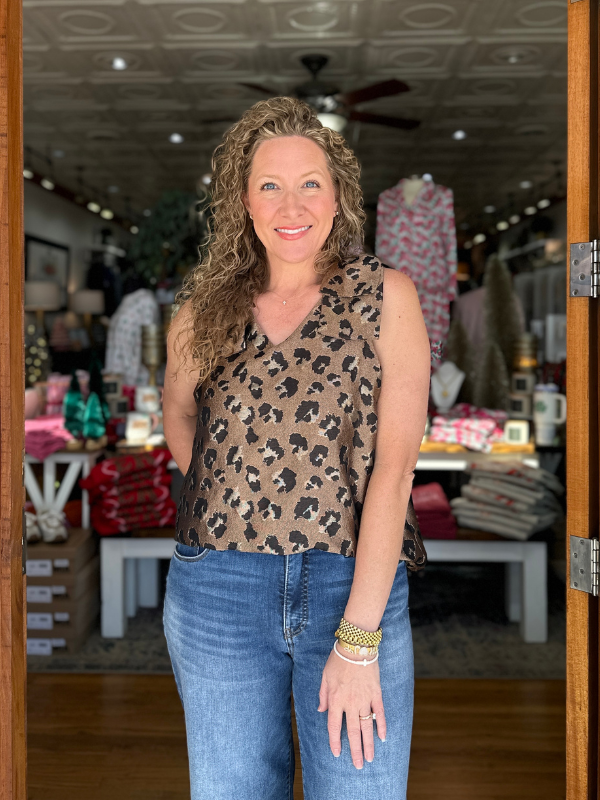 Woman wearing a leopard print top and blue jeans standing in a store.