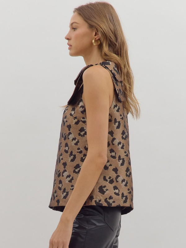 Woman wearing a sleeveless leopard print top against a plain background
