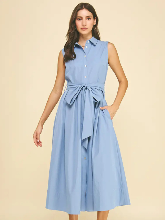 Woman wearing a light blue dress with a belt on a beige background