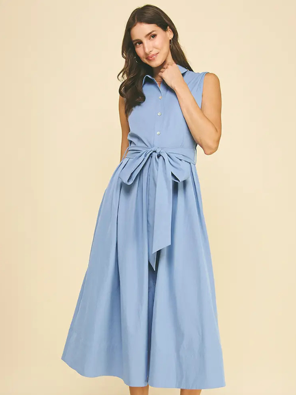 Woman wearing a light blue dress with a belt on a beige background