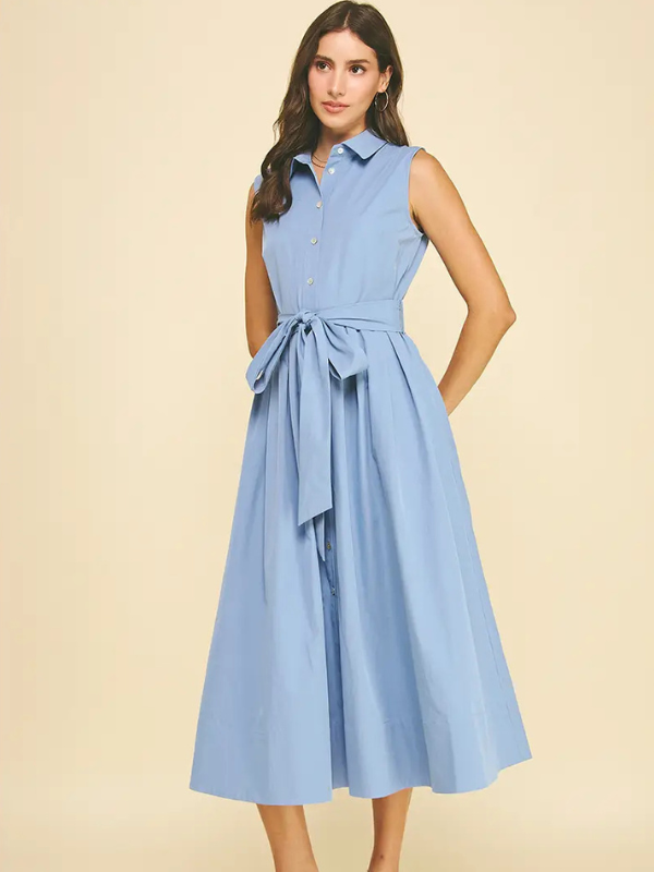 Woman wearing a light blue dress with a belt on a beige background